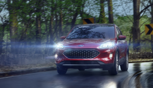 The 2021 Ford Escape driving down a street with it's headlights on