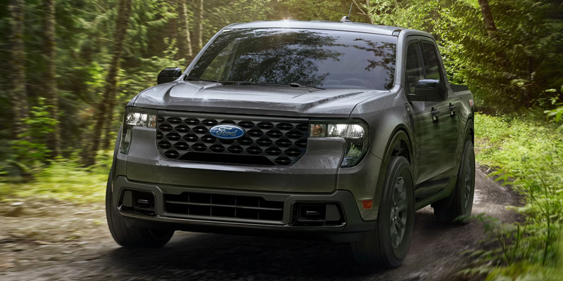 Ford Maverick truck driving through a forest trail.